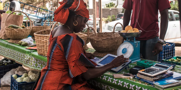 Une femme sur un marché de Dakar traite une commande de légumes à l’aide de sa tablette Weebi. © Vincent Tremeau / La Banque mondiale